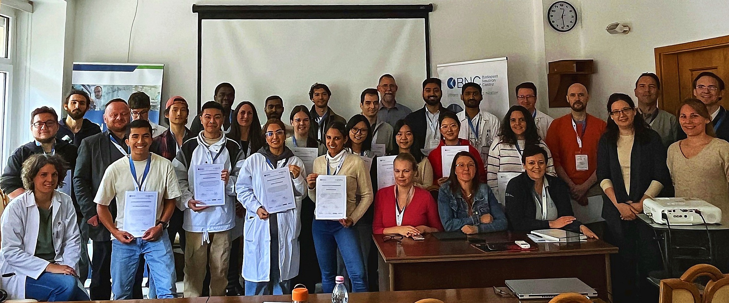 CETS 2026 participants holding their certificates during a group photo with lecturers and organisers at the Budapest Neutron Centre.