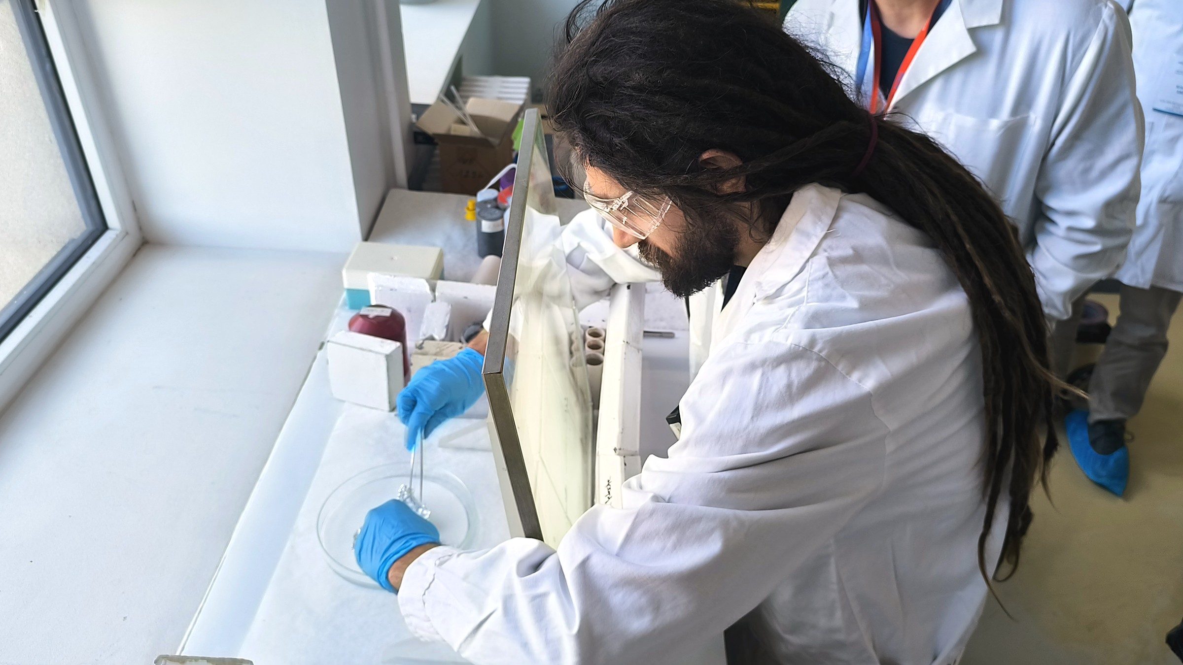 Unpacking a radioactive sample with tweezers behind protective shielding during a CETS 2026 practical session at the Budapest Neutron Centre.